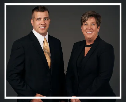 Two professionals in formal attire, wearing suits and ties, engaged in a business discussion.