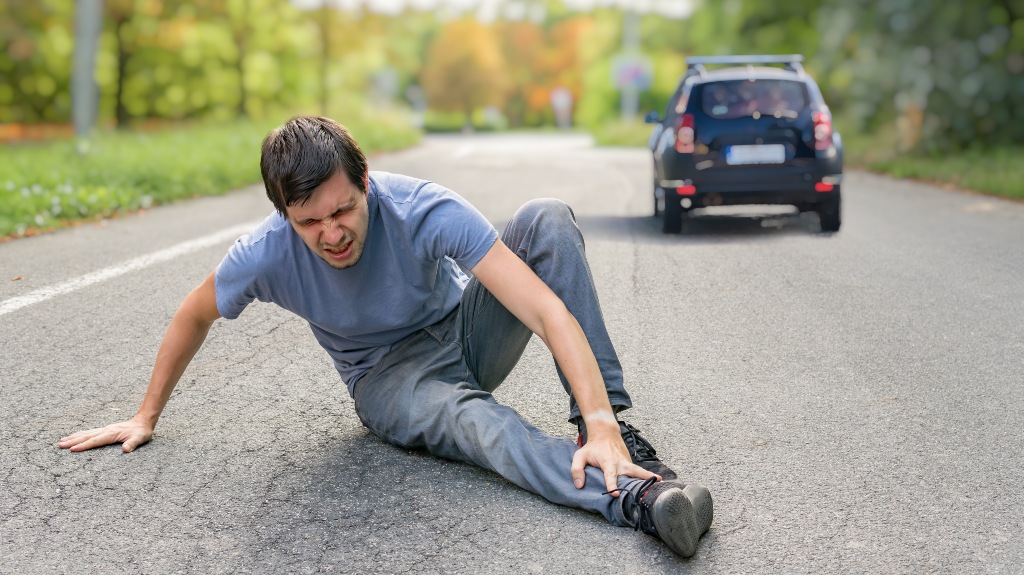 Injured man on road in front of a car