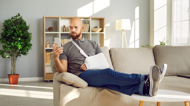 Man with broken arm using mobile phone
