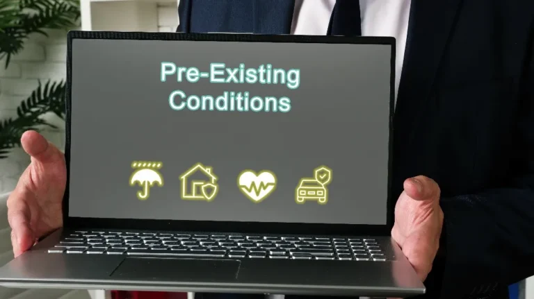 Person in dark suit holding laptop displaying "Pre-Existing Conditions" text.